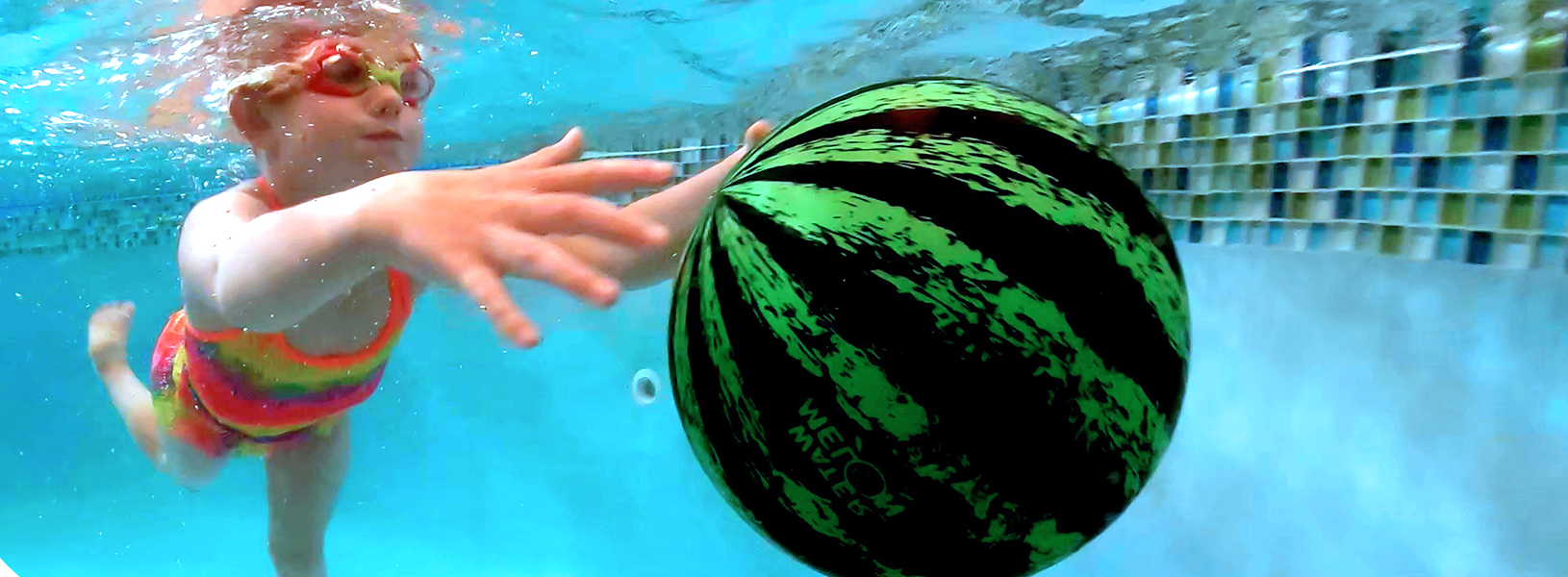 A swimmer reaching for a filled watermelon ball under the surface of a pool